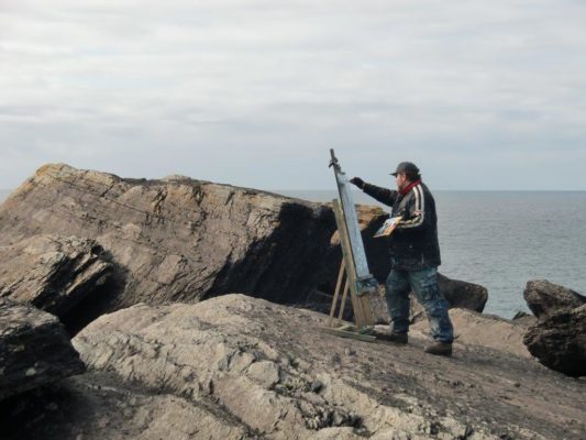 Perched on the edge of the world, Rod Coyne paints on Valentia Island, Co. Kerry.