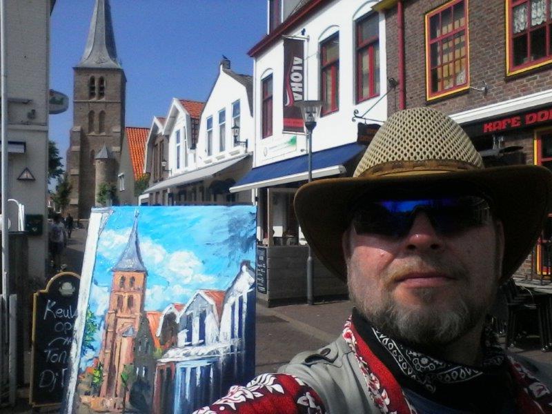 Photo of rod coyne's last day painting in domburg. mondriaan's church, and rod's piainting of same, visible over the artists shoulder