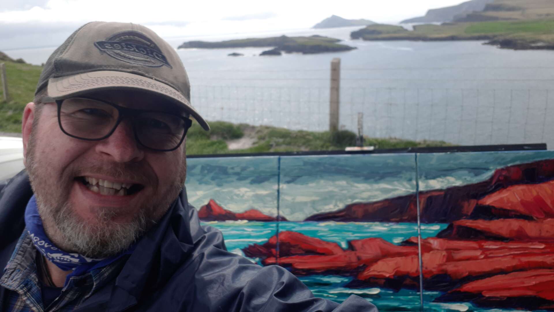 photo of rod coyne, just finished his painting of puffin sound, the painting is on the easel behind him and puffin sound is just behind that.